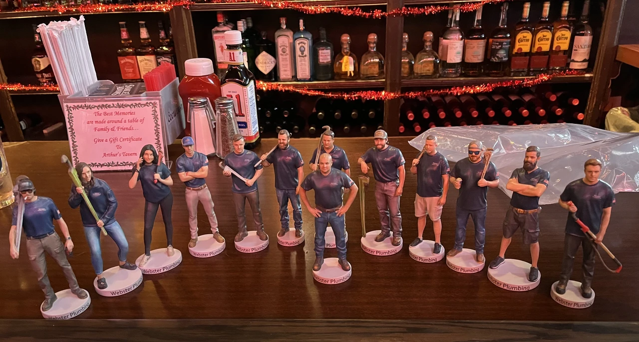 A lineup of 3D-printed corporate team figurines displayed on a bar
