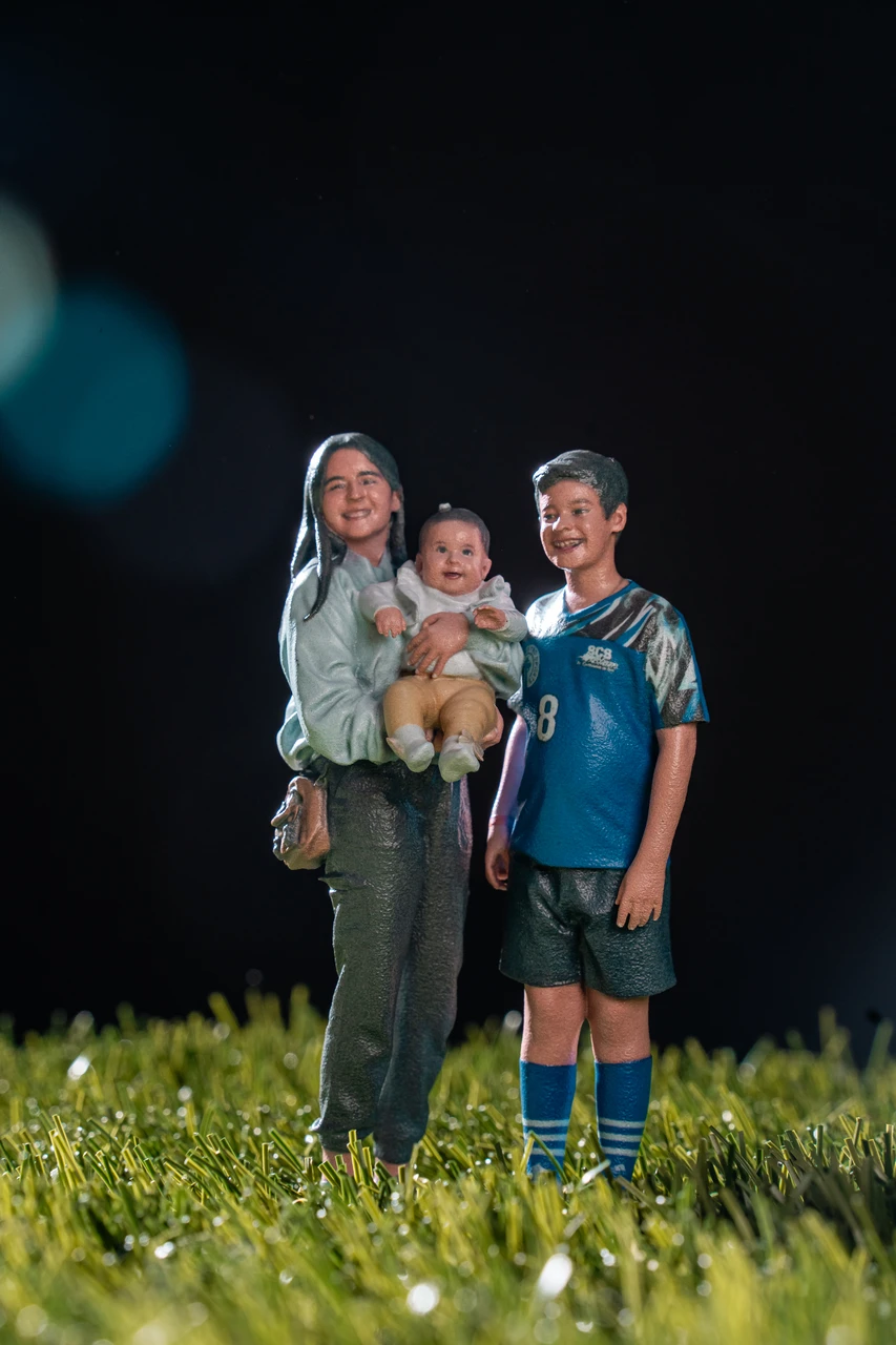 3D-printed replica of a mother holding a baby beside a young soccer player